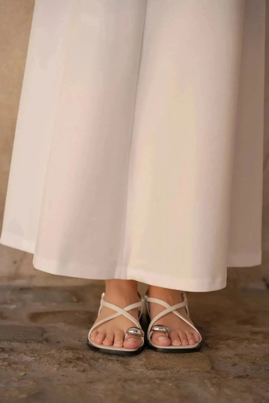 Zoom sur les sandales portées avec une robe longue blanche chic, montrant comment l'élégance se marie avec le confort.