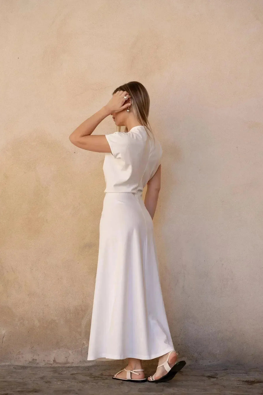 Aperçu arrière d'une jeune femme dans une robe longue blanche chic à manches courtes, soulignant le confort et le style du tissu doux.