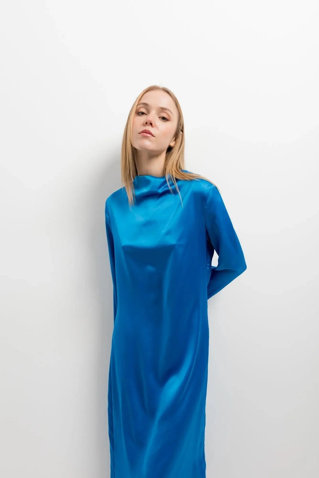 Femme portant une robe satinée bleu électrique à manches longues et col montant