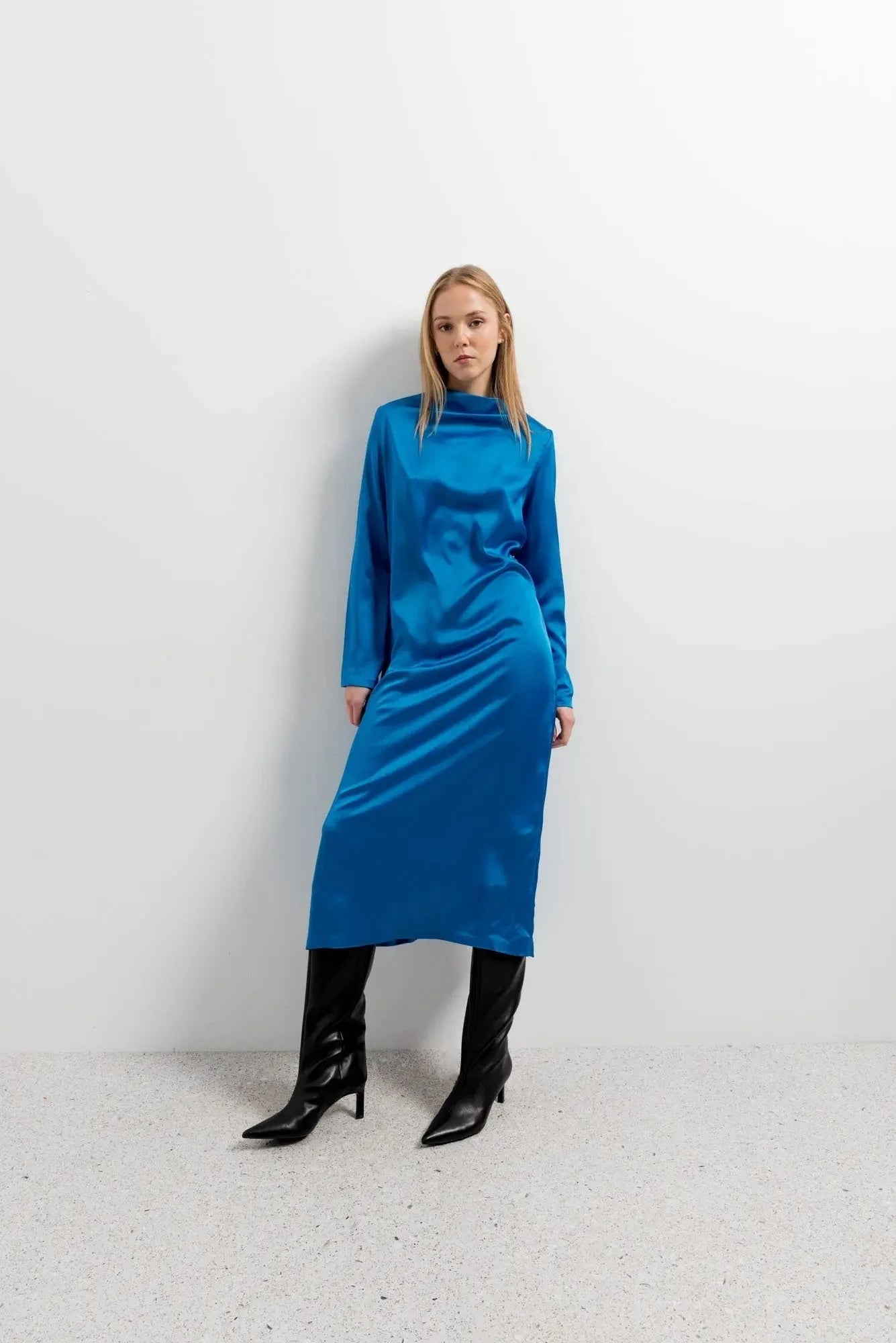 Femme portant une robe satinée bleu électrique à manches longues et col montant
