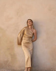 Jeune femme posant avec la Robe Dorée Satinée Asymétrique Une Manche Avec Fente Latérale, mettant en valeur son élégance pour soirées chic.