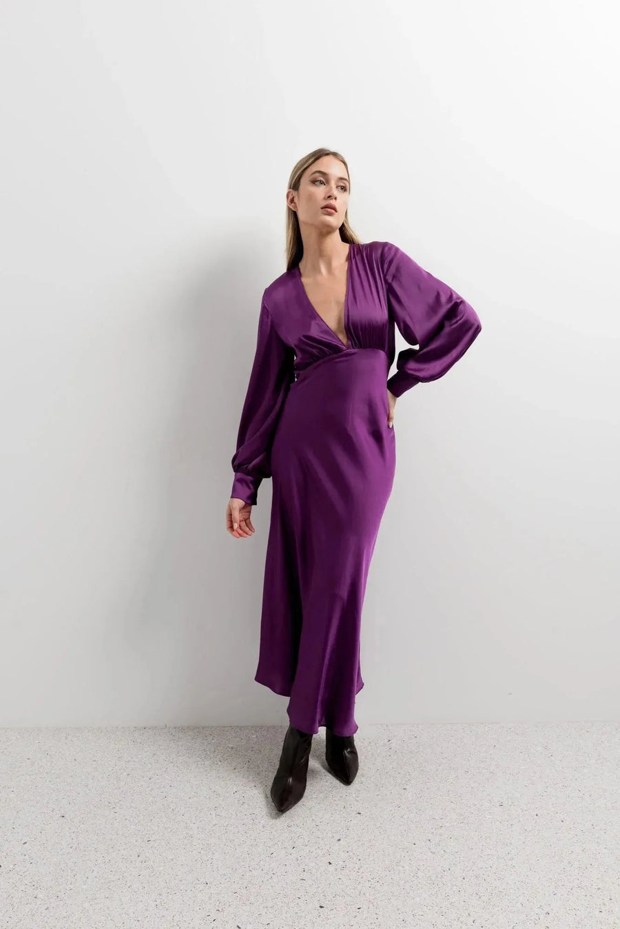 Femme posant en robe midi satinée violette à manches longues, parfait pour une robe soirée en satin, combinant confort et sophistication.