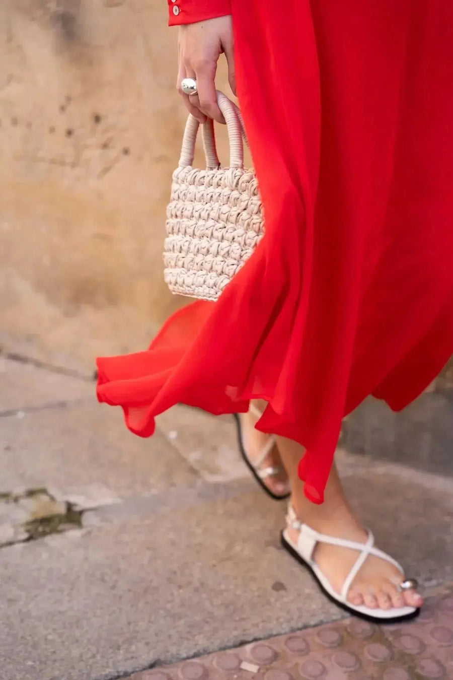 Femme marchant avec une robe mousseline rouge midi et des sandales, mettant en valeur la fluidité de la robe à décolleté plongeant.