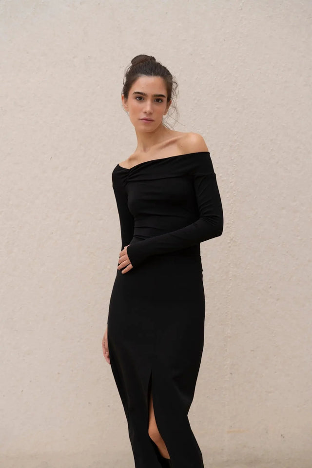 Gros plan sur la robe noire longue femme élégante, mise en avant sa coupe et fente midi.