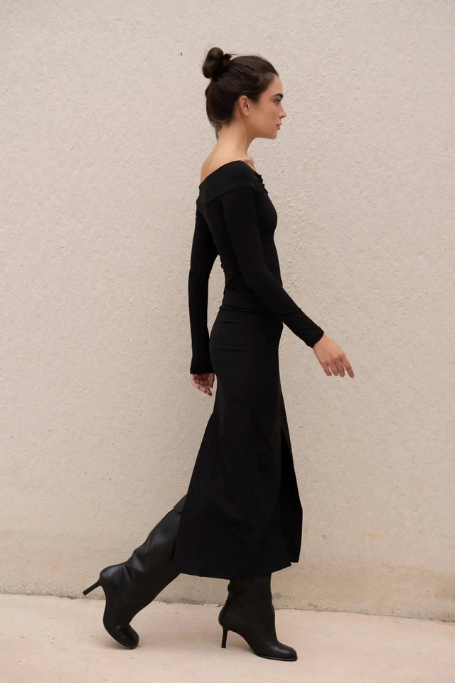 Silhouette de femme marchant avec une robe noire longue femme élégante, fente midi visible.