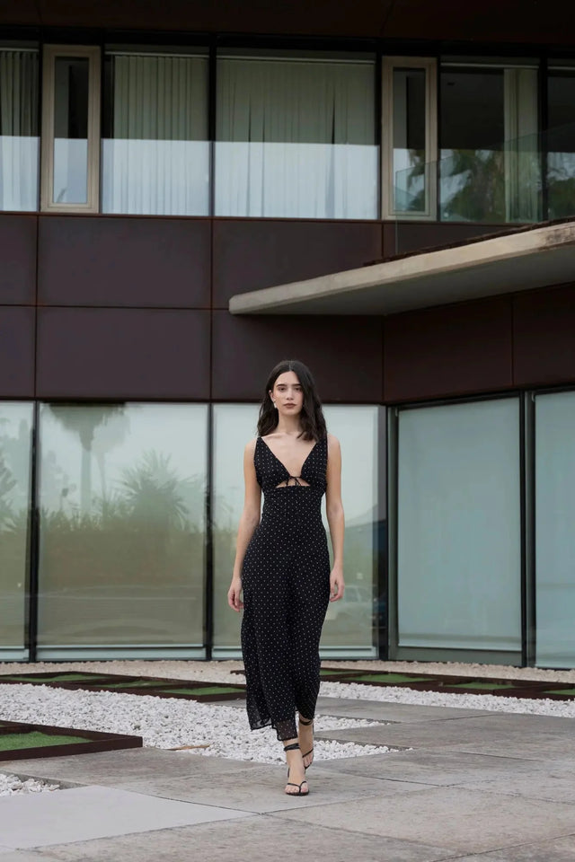 Modèle s'avançant avec confiance dans la robe noire à pois blanc, mettant en valeur son style chic pour une soirée d'été.