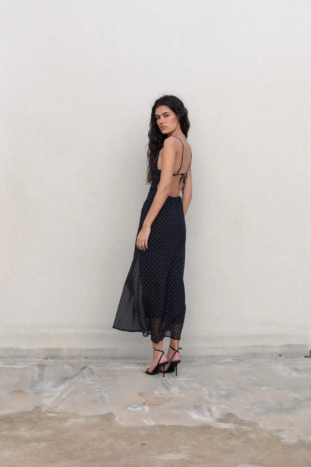 Vue latérale du modèle portant la robe noire à pois blanc, mettant en avant le design flatteur et chic.