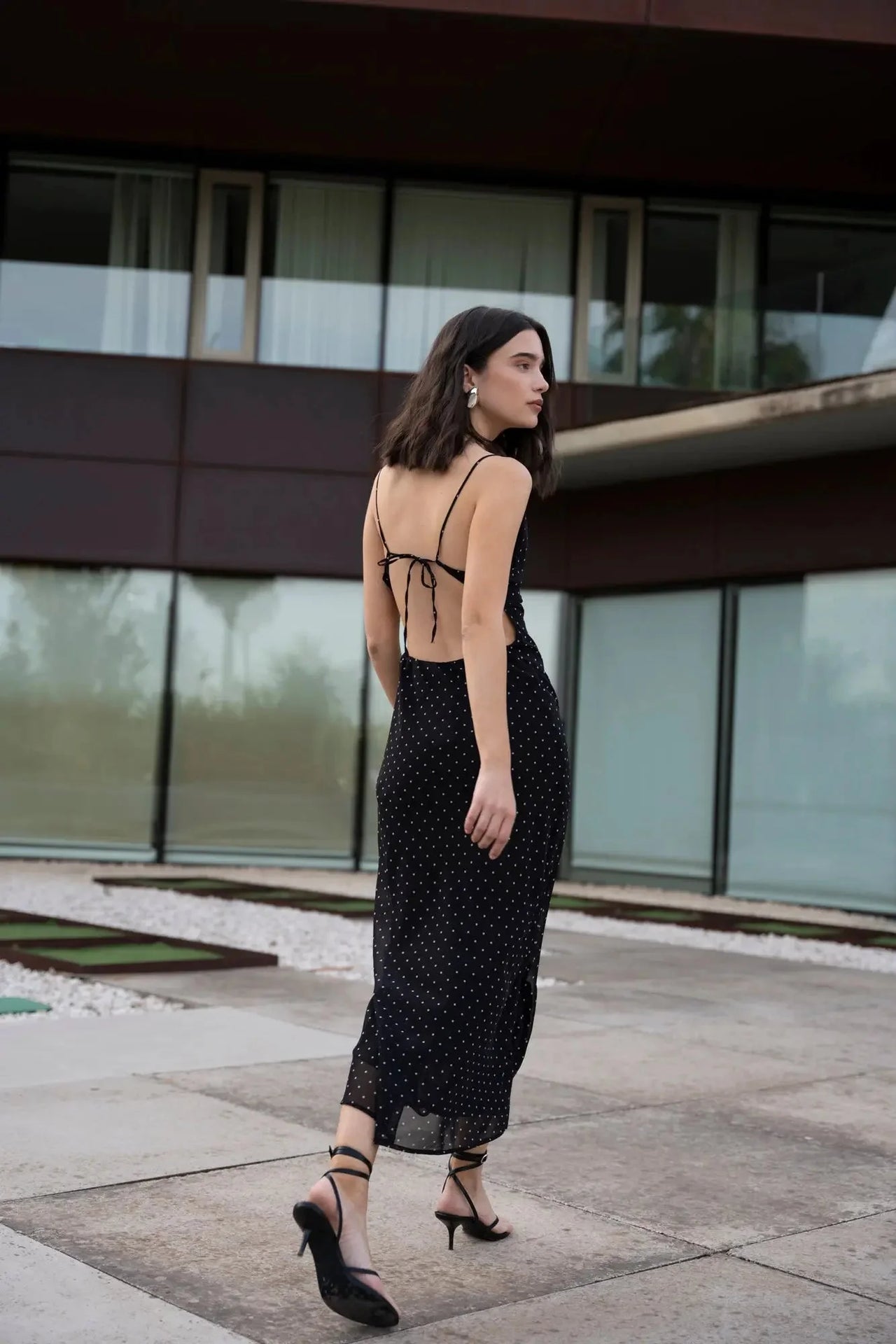 Vue arrière de la robe noire à pois blanc, montrant le dos nu et les détails de la coupe, idéale pour un look estival.