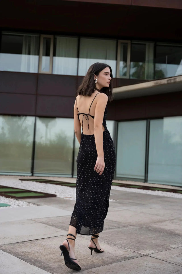 Vue arrière de la robe noire à pois blanc, montrant le dos nu et les détails de la coupe, idéale pour un look estival.