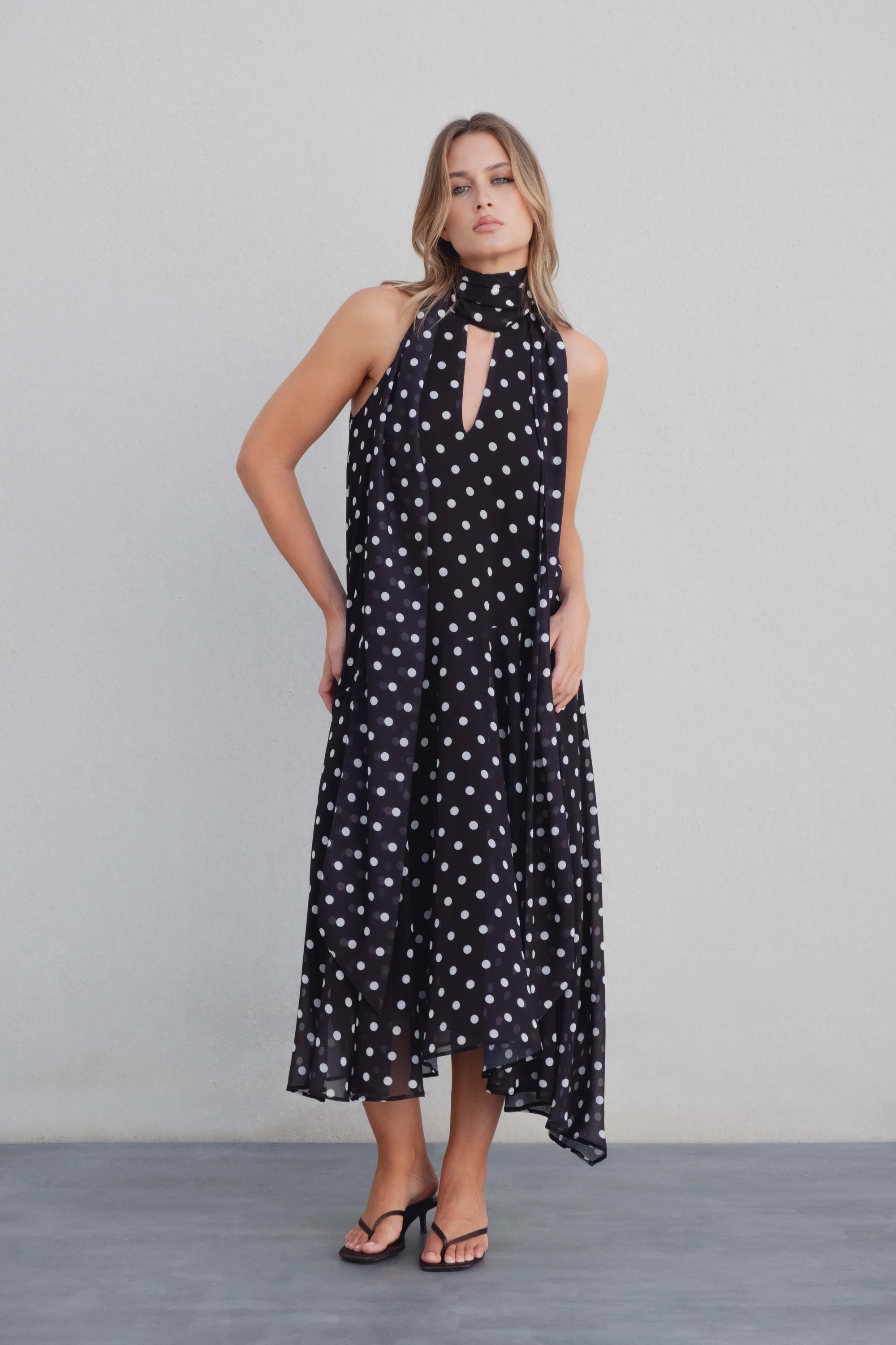 Robe noire à pois blancs fluide – col noué et coupe asymétrique Sapiato