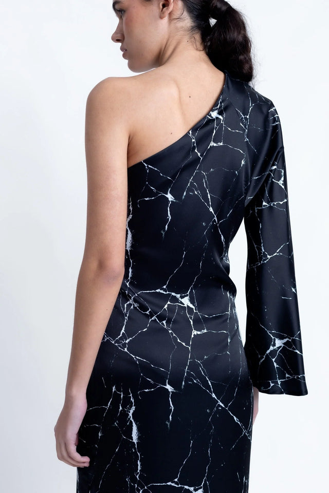 Femme montrant la Robe de Soirée Femme Asymétrique Satinée Noire Avec Imprimé Marbre, en focus sur le dos et les détails de la manche.