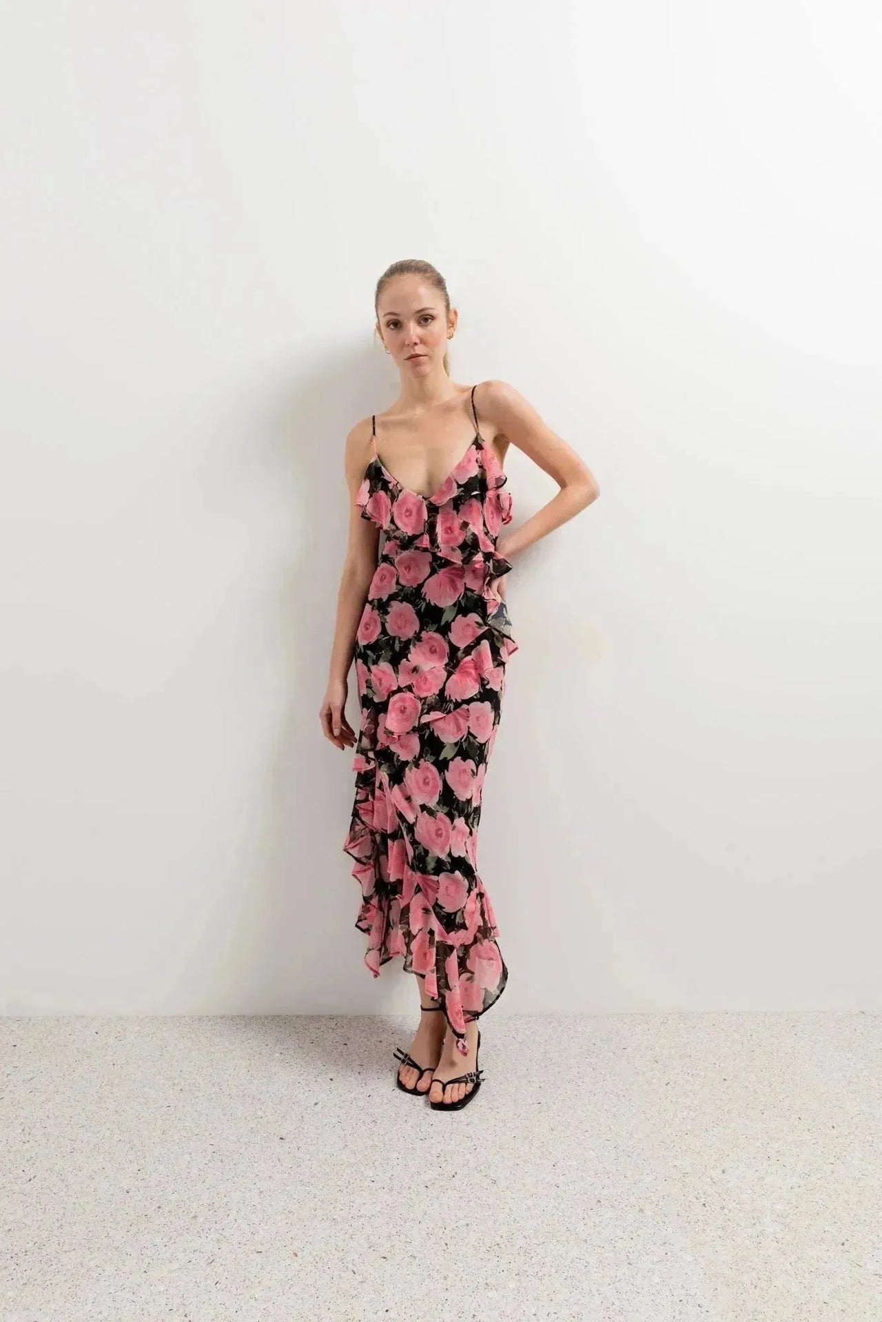 Modèle en pose posant avec assurance dans une robe longue fleurie femme à volants rose bohème chic en viscose noir, prête pour toute occasion.