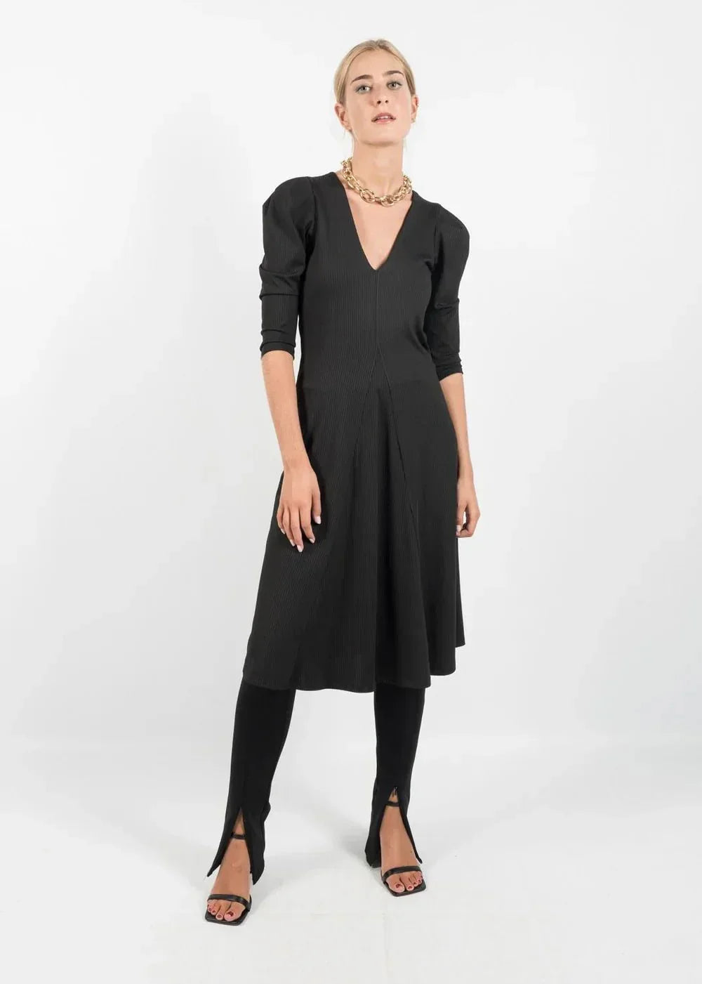 Robe noire mi-longue avec manches bouffantes, leggings et talons ouverts, élégance assurée