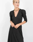 Détail d'une robe manche bouffante mi longue noir col V en tissu côtelé stretch, soulignant le confort et l'élégance de la silhouette.