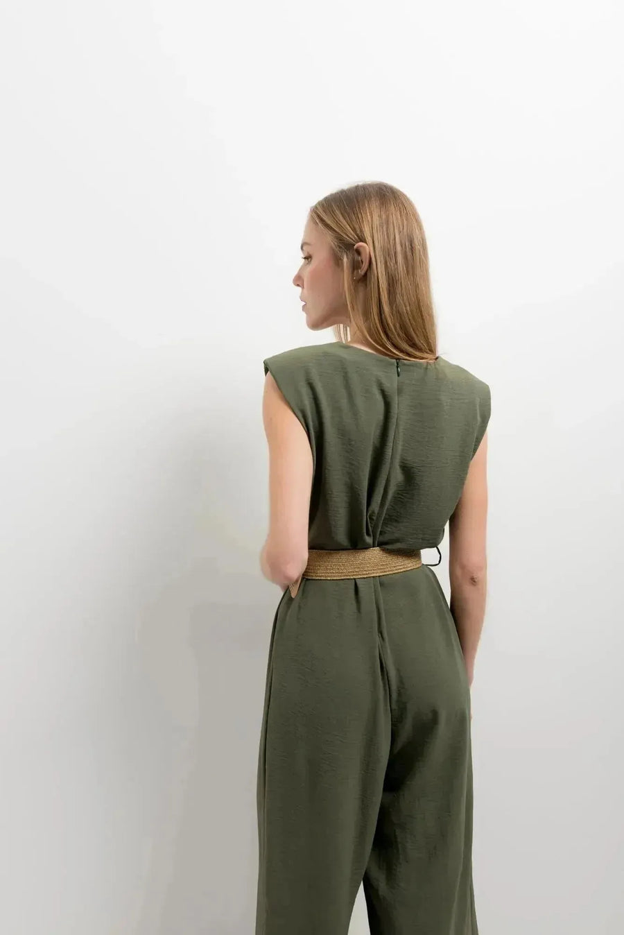 Vue arrière d'une femme dans une combinaison femme chic olive, sans manches, montrant le design soigné, idéal pour toutes les occasions.