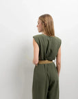 Vue arrière d'une femme dans une combinaison femme chic olive, sans manches, montrant le design soigné, idéal pour toutes les occasions.