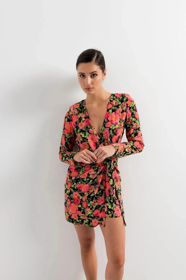 Woman mettant en valeur sa robe portefeuille femme fleuri noir et rose, courte à manches longues avec décolleté en V, pour un style chic et contemporain.