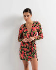 Woman mettant en valeur sa robe portefeuille femme fleuri noir et rose, courte à manches longues avec décolleté en V, pour un style chic et contemporain.