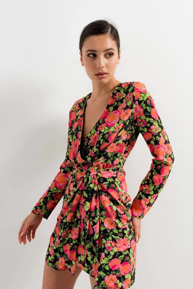 Modèle portant une robe portefeuille femme fleuri noir et rose, courte à manches longues avec décolleté en V, idéale pour un look élégant.