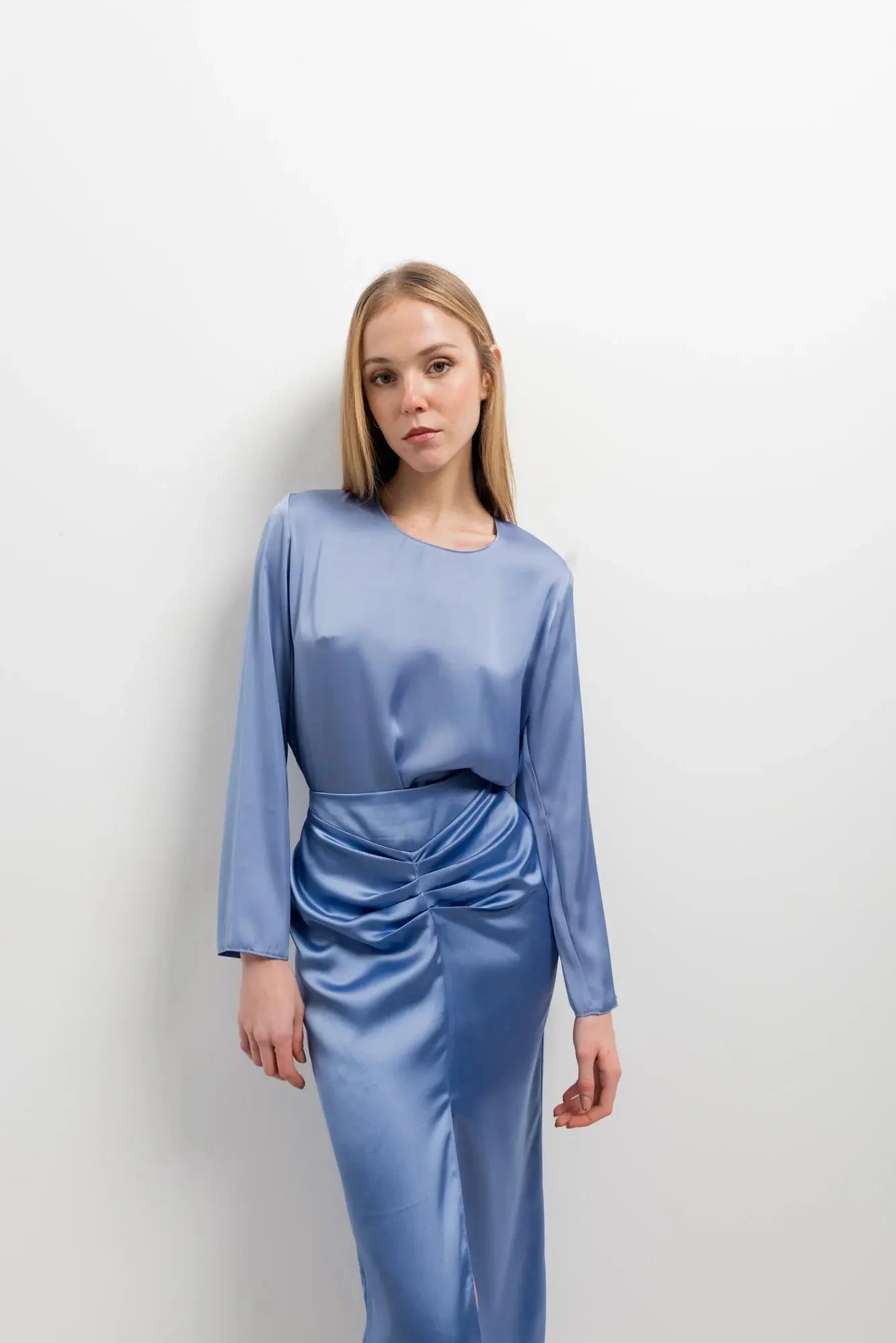 Femme portant une robe en satin bleu pervenche à manches longues avec taille froncée
