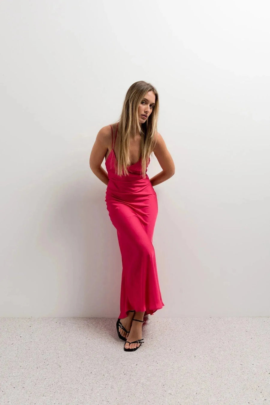 Femme en robe dos nu satin rouge éclatant, affichant un look élégant et décontracté avec décolleté drapé.