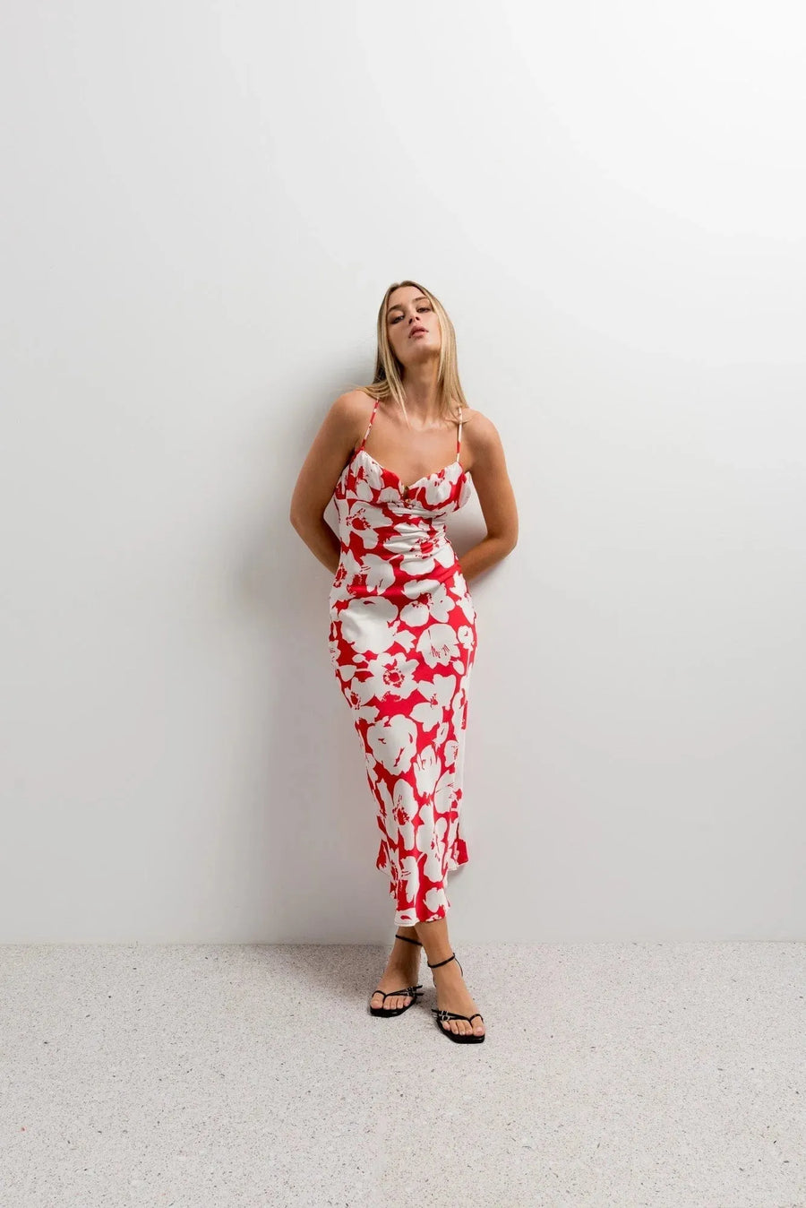 Modèle portant une robe satinée rouge à imprimé floral, robe camisole, avec bretelles croisées et une silhouette fluide.