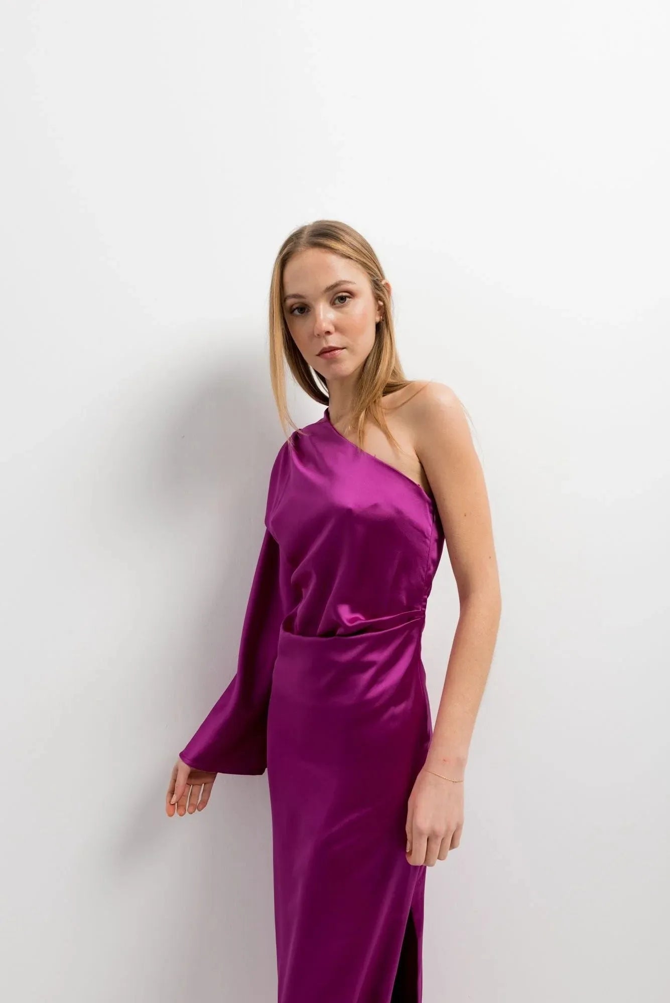 Gros plan sur un modèle portant la robe midi asymétrique rose fuchsia en satin à une épaule, un choix chic pour les événements formels. Robe asymétrique de soirée.