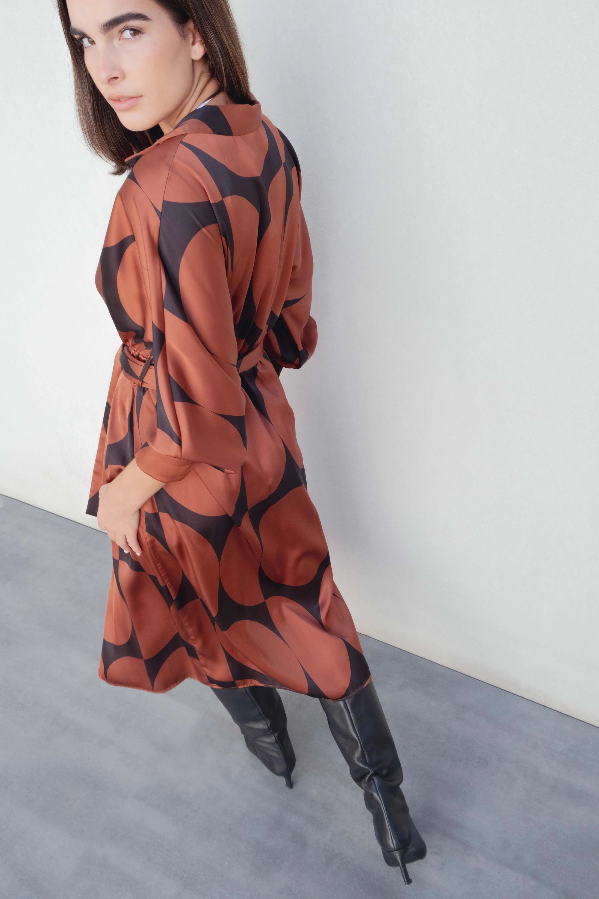 Vue de dos du modèle dans la Robe Portefeuille Femme À Imprimé Géométrique Noir & Marron, soulignant le design fluide et élégant.