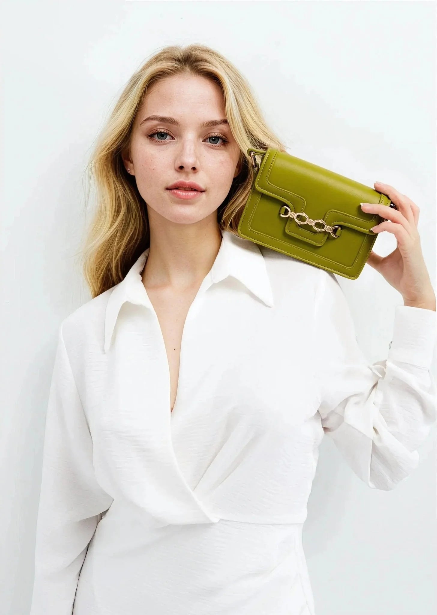 Femme blonde avec sac à main crossbody blanc à boucle, portant une robe blanche
