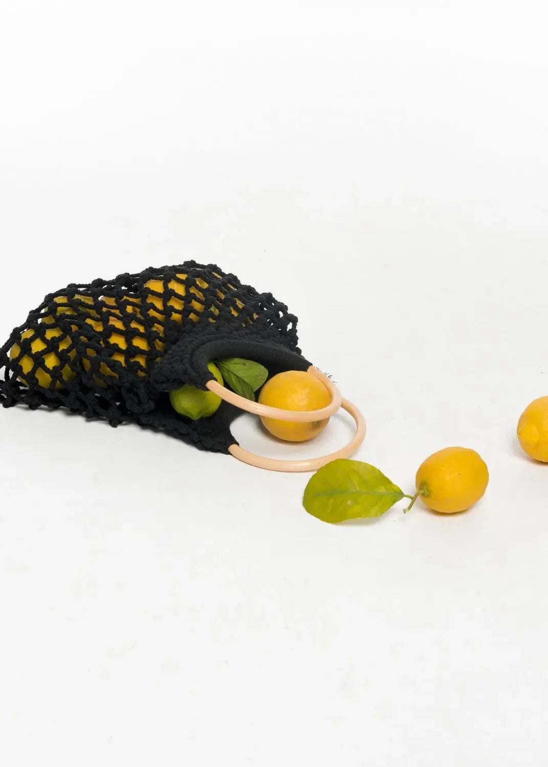 Sac à main noir en mesh rempli de citrons et de limes, élégant et pratique