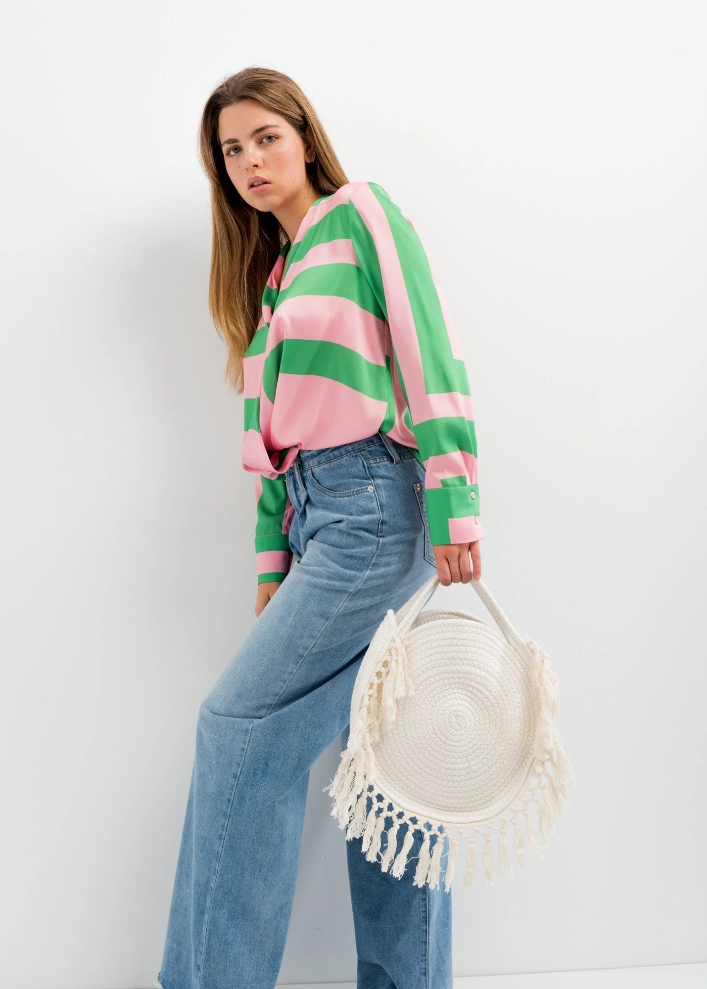 Femme avec sac panier rond en macramé à franges, veste à rayures rose et vert