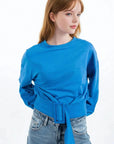 Femme portant un sweat-shirt court bleu ceinturé pour un look plus chic et décontracté