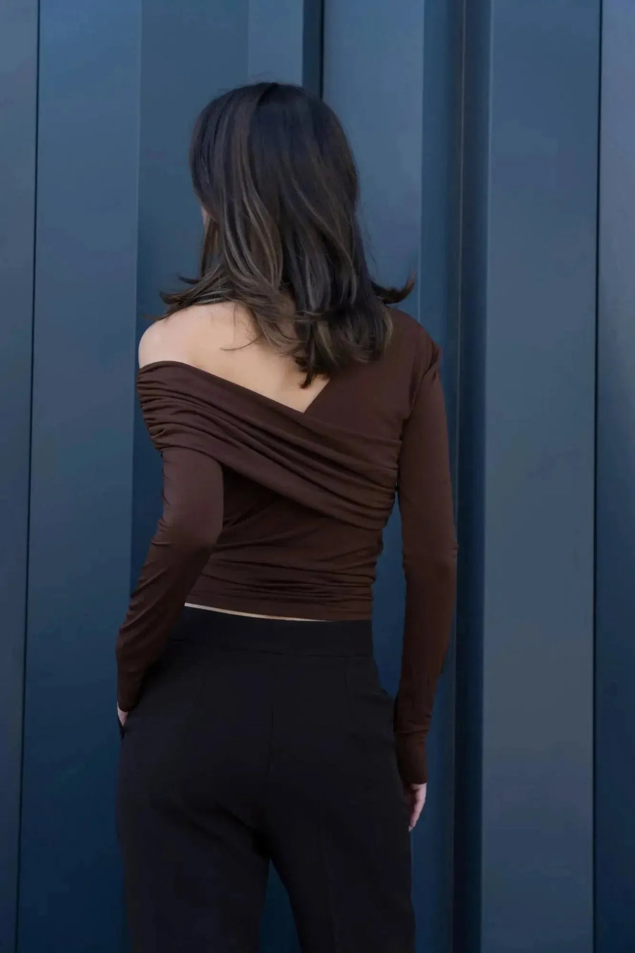 Vue arrière d'une femme dans un T-shirt asymétrique brun, illustrant le design innovant et tendance. T shirt asymétrique femme.