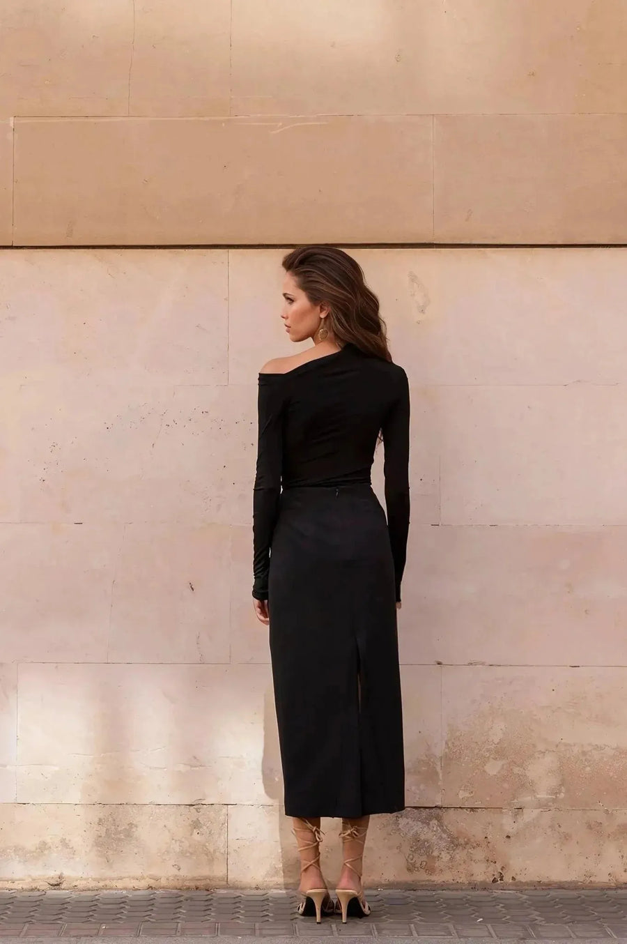 Femme portant un t-shirt asymétrique noir à manches longues et une jupe midi avec fente