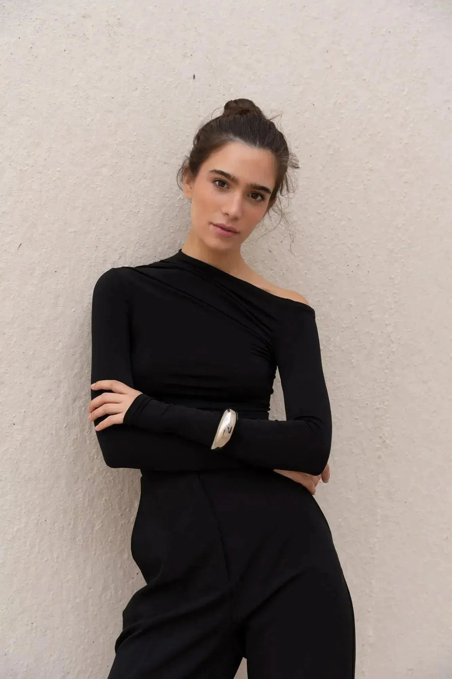 Femme portant un t-shirt asymétrique noir à manches longues et pantalons noirs
