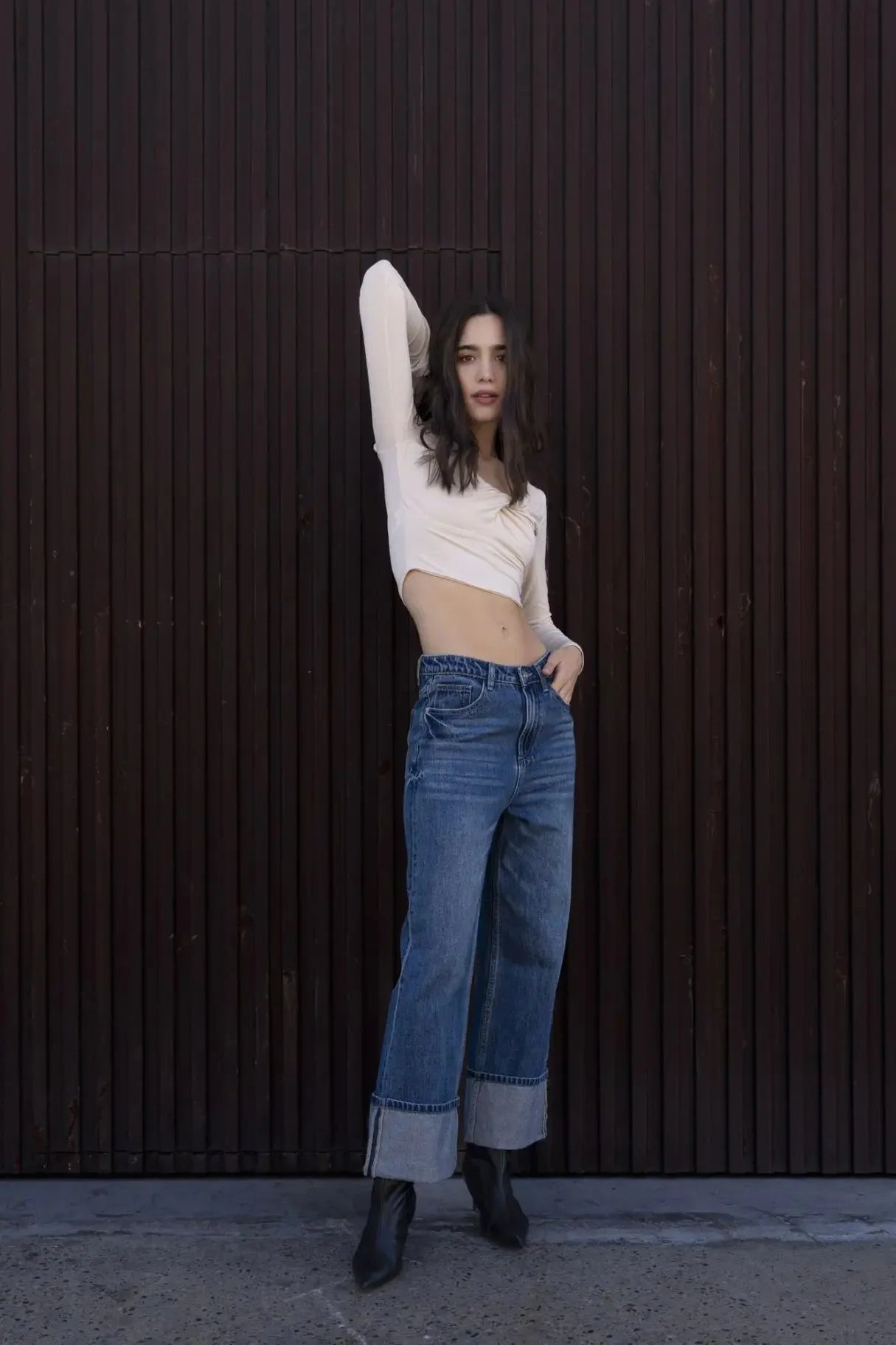 Cadrage d'une femme dans un T-Shirt Crop Top Manche Longue Avec Noeud Élégant Pour Femme, arborant un style casual au milieu d'un décor sobre.