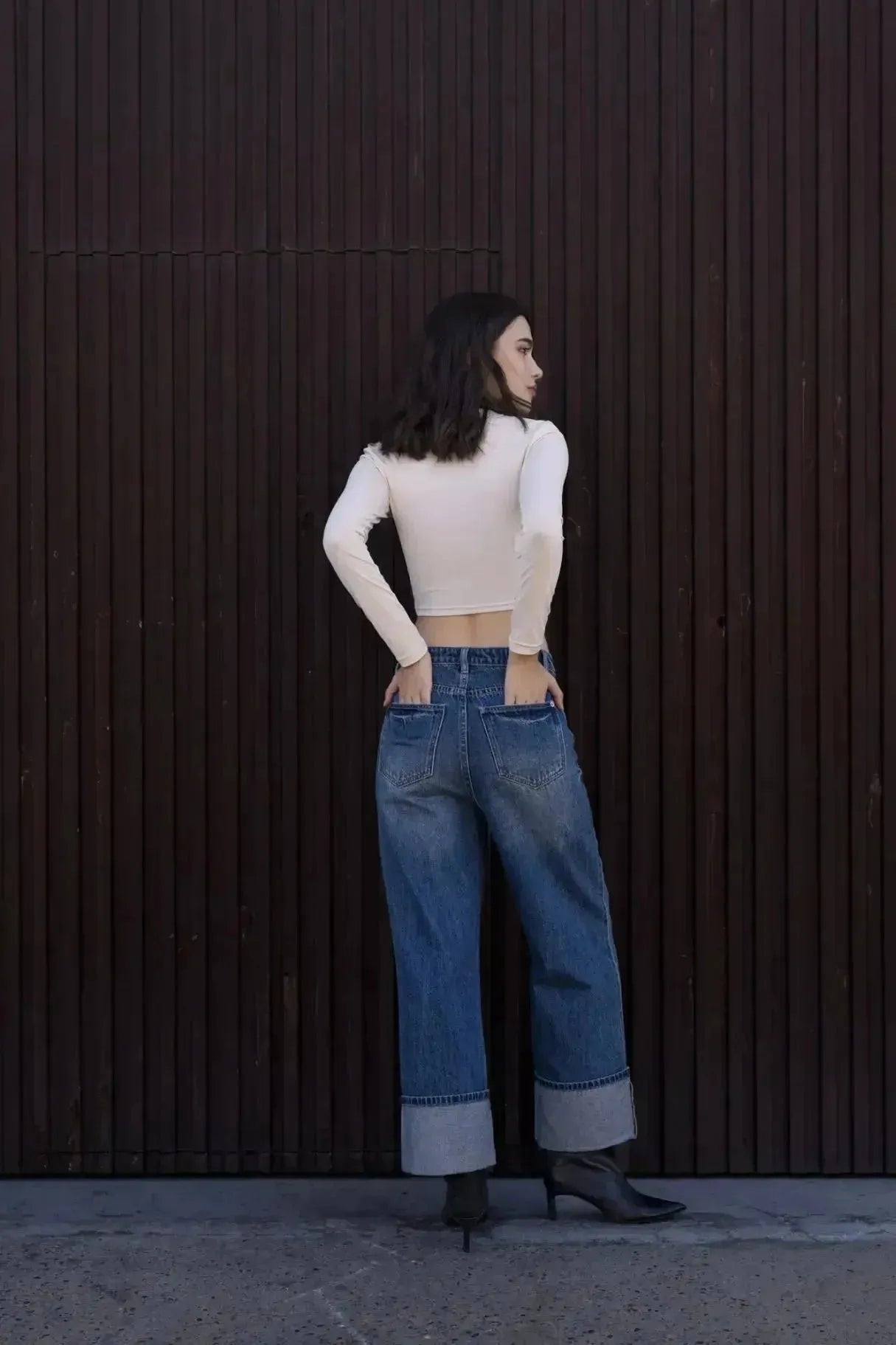 Femme posant dans un T-Shirt Crop Top Manche Longue Avec Noeud Élégant Pour Femme, stylée et chic, les mains dans les poches d'un jean.