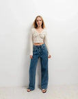Femme souriante en T-Shirt Crop Top Manche Longue Avec Noeud Élégant Pour Femme, associée à un jean, idéale pour des occasions variées.