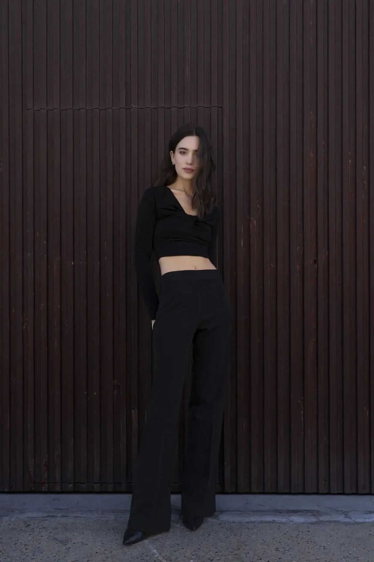 Femme posant en T-Shirt Crop Top Manche Longue Avec Noeud Élégant Pour Femme, associé à des pantalons noirs, pour un look chic et moderne.