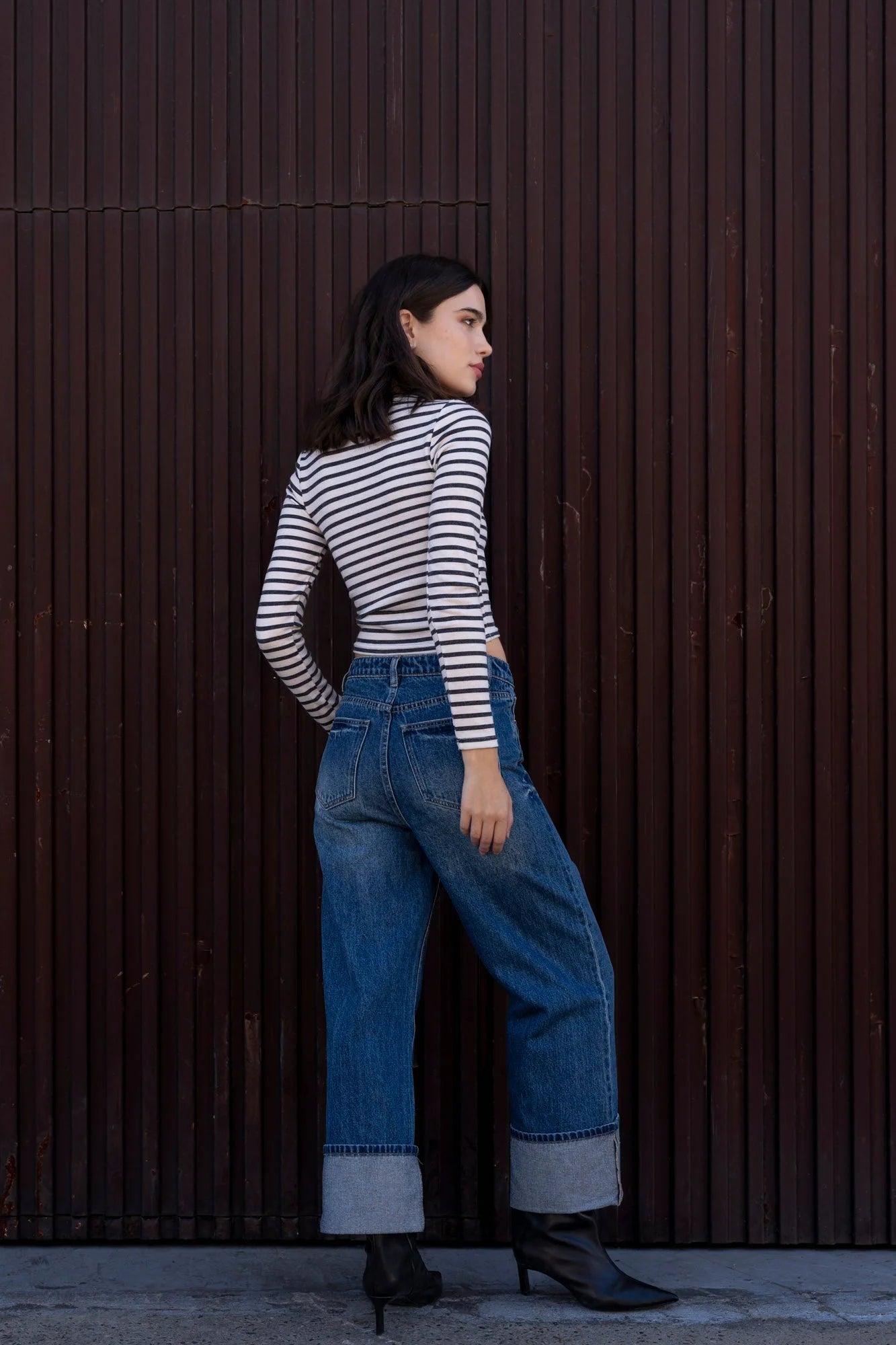 Femme portant un t-shirt marinière à manches longues, jeans large et bottes à talons