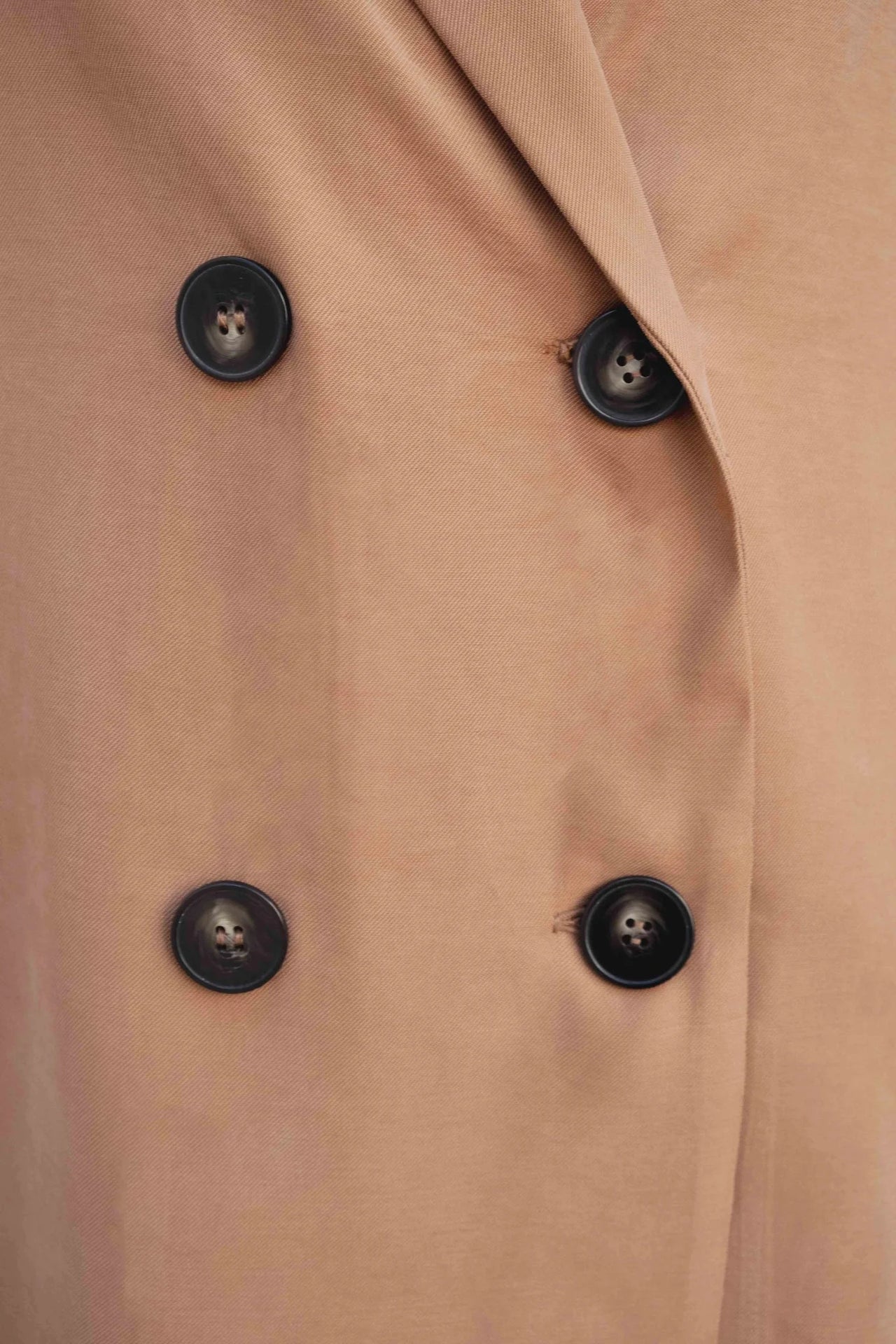 Détail des boutons noirs sur un blazer fluide camel, mettant en valeur le design élégant.