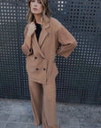 Femme portant un tailleur blazer oversize croisé fluide camel, style chic décontracté avec un pantalon assorti.