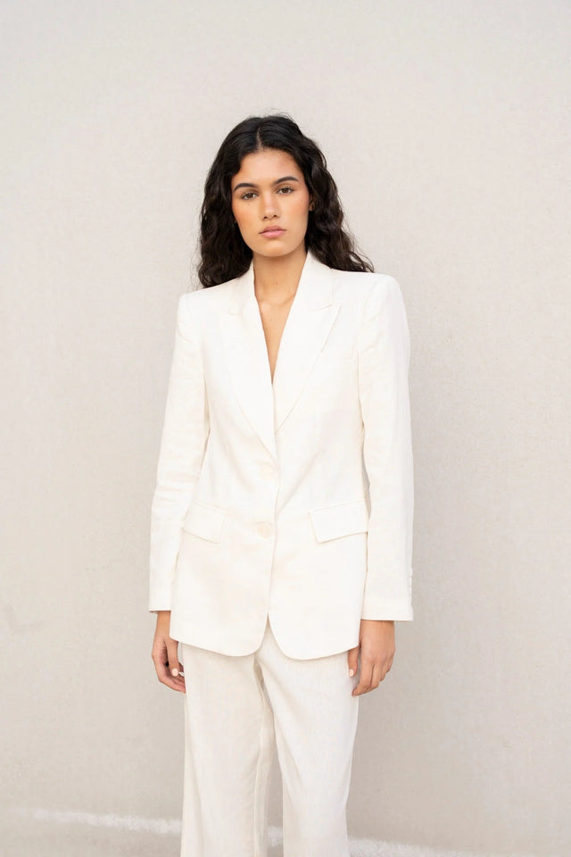Portrait d'une femme avec un blazer blanc femme en lin naturel, ajoutant une touche d'élégance pour l'été.