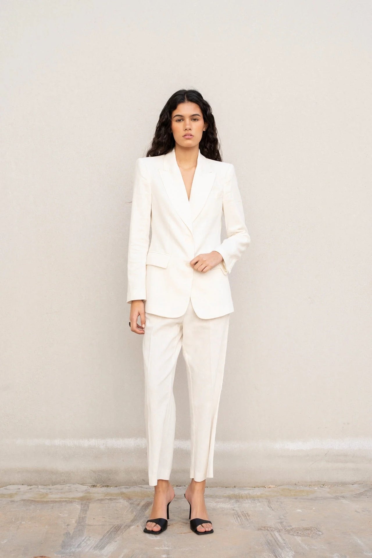 Modèle portant un blazer blanc femme en lin naturel, élégant et cintré pour l'été et mi-saison.