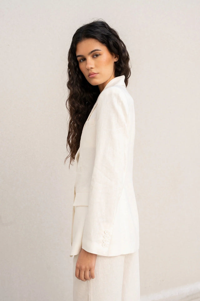 Femme stylée avec un blazer blanc femme en lin naturel, ajoutant une caractéristique intemporelle à sa tenue.