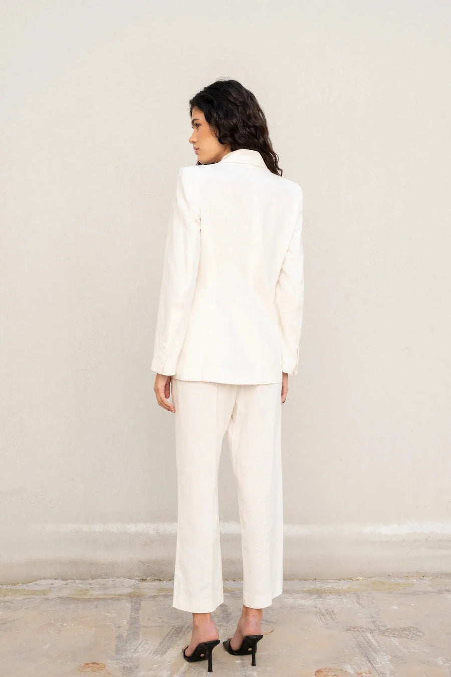 Femme de dos avec un blazer blanc femme en lin naturel, parfait pour une allure chic en été.