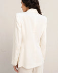 Vue arrière d'une femme portant un blazer blanc femme en lin naturel, soulignant la coupe structurée.