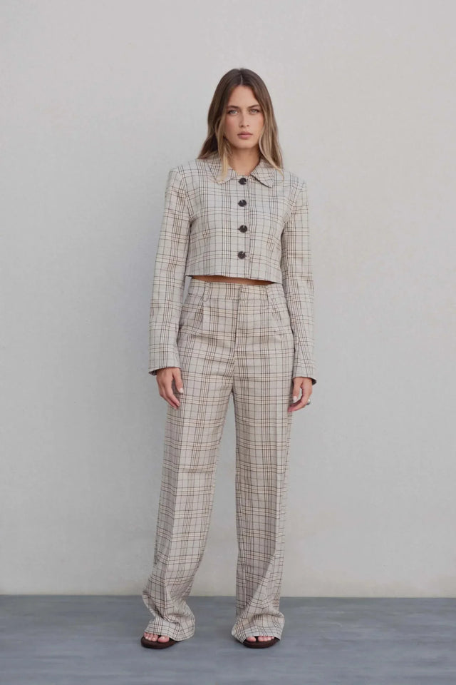 Modèle féminin posant avec un tailleur pantalon à carreaux beige look structuré, combinaison élégante avec une coupe droite, idéale pour le bureau et les sorties. Pantalon femme carreaux.