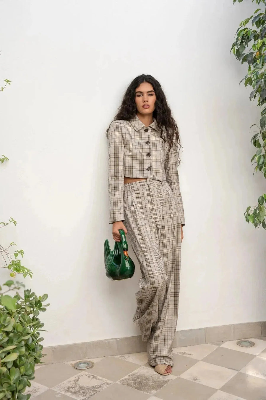 Femme au style décontracté portant un tailleur pantalon à carreaux beige look structuré, accompagné d'un sac original, parfait pour une allure casual chic. Pantalon femme carreaux.