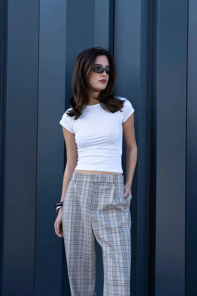 Modèle posant en extérieur avec un tee-shirt blanc et un tailleur pantalon à carreaux beige look structuré, affichant un look moderne et élégant. Pantalon femme carreaux.